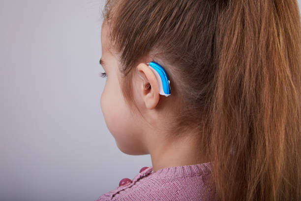 Hearing Aid in Young Girl's Ear. Toddler girl wearing a hearing aid. Studio shot